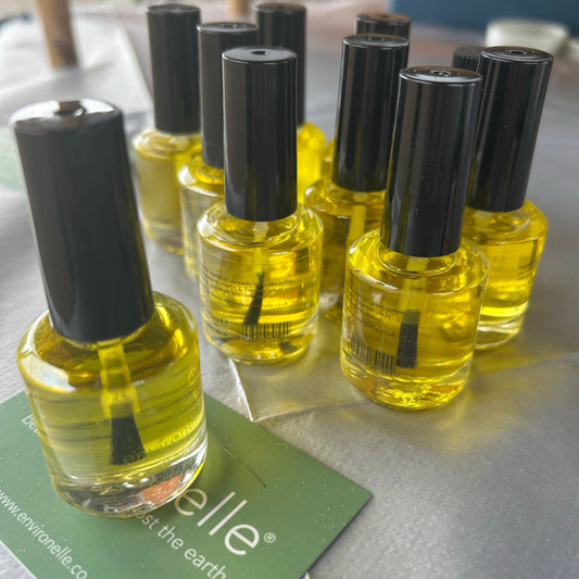 Set of small yellow bottles with black caps on a metallic surface, with a green card in the background.